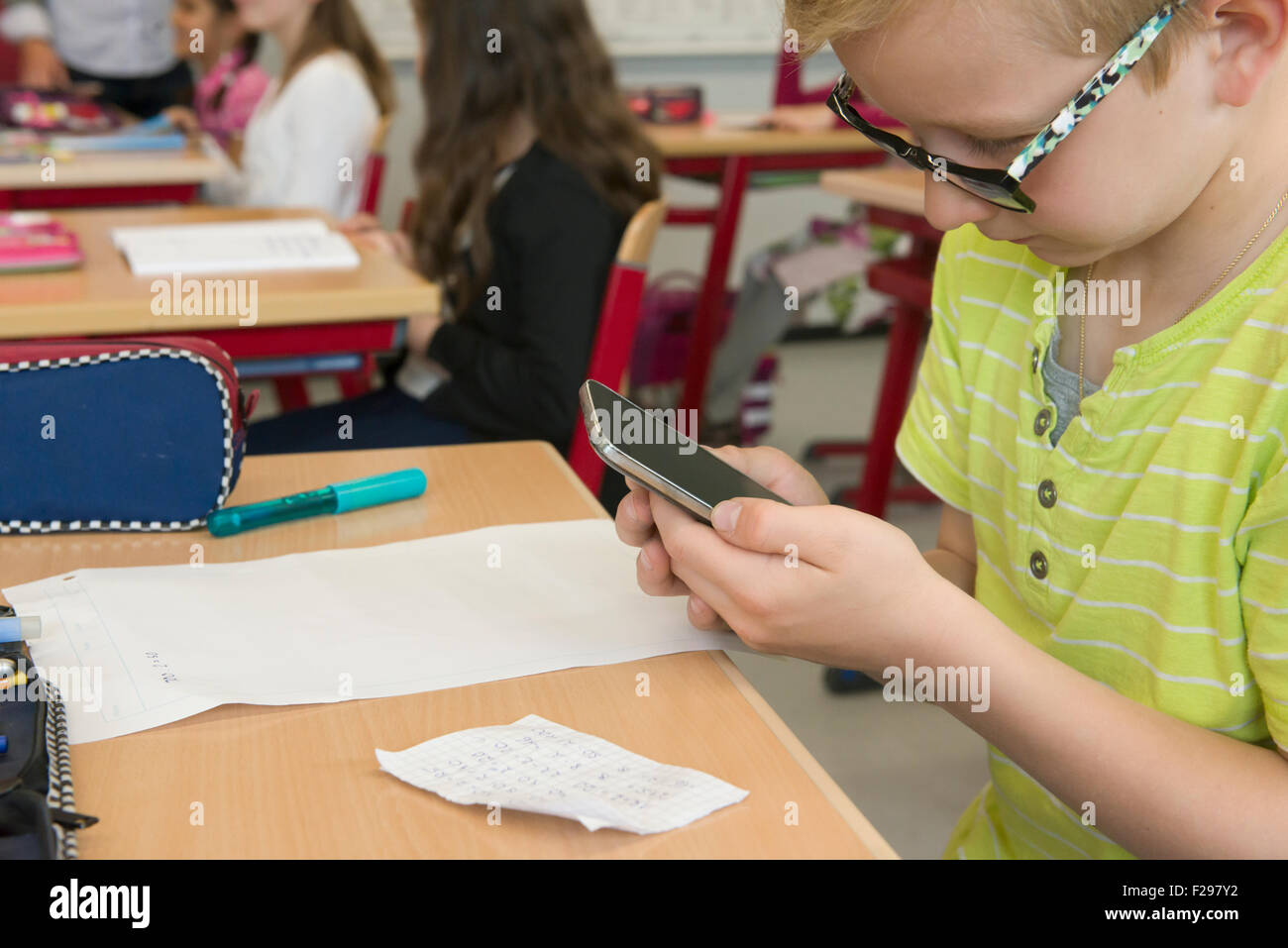 Close-up of a schoolboy using smart phone in classroom, Munich, Bavaria, Germany Stock Photo