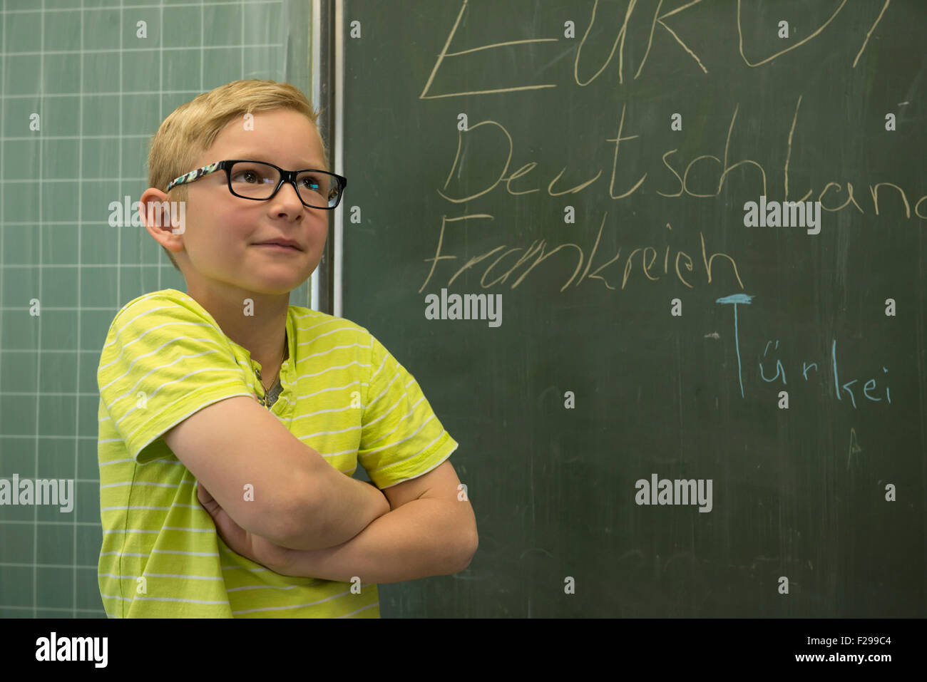 schoolboy standing in front of blackboard in classroom, Munich, Bavaria, Germany Stock Photo