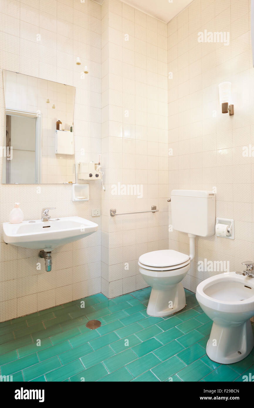 Simple, old bathroom with green tiled floor Stock Photo