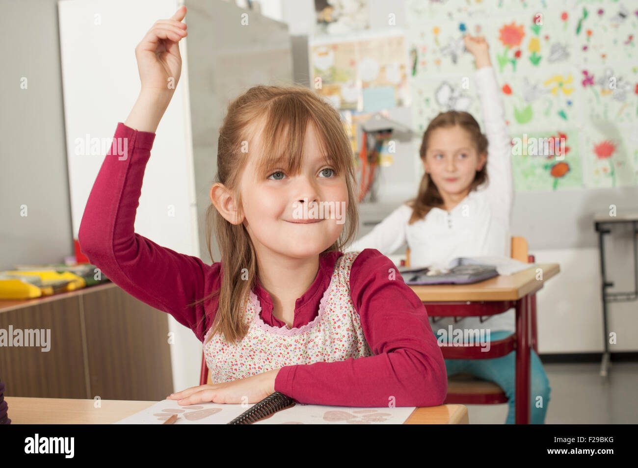 school children with raised hands in classroom, Munich, Bavaria, Germany Stock Photo
