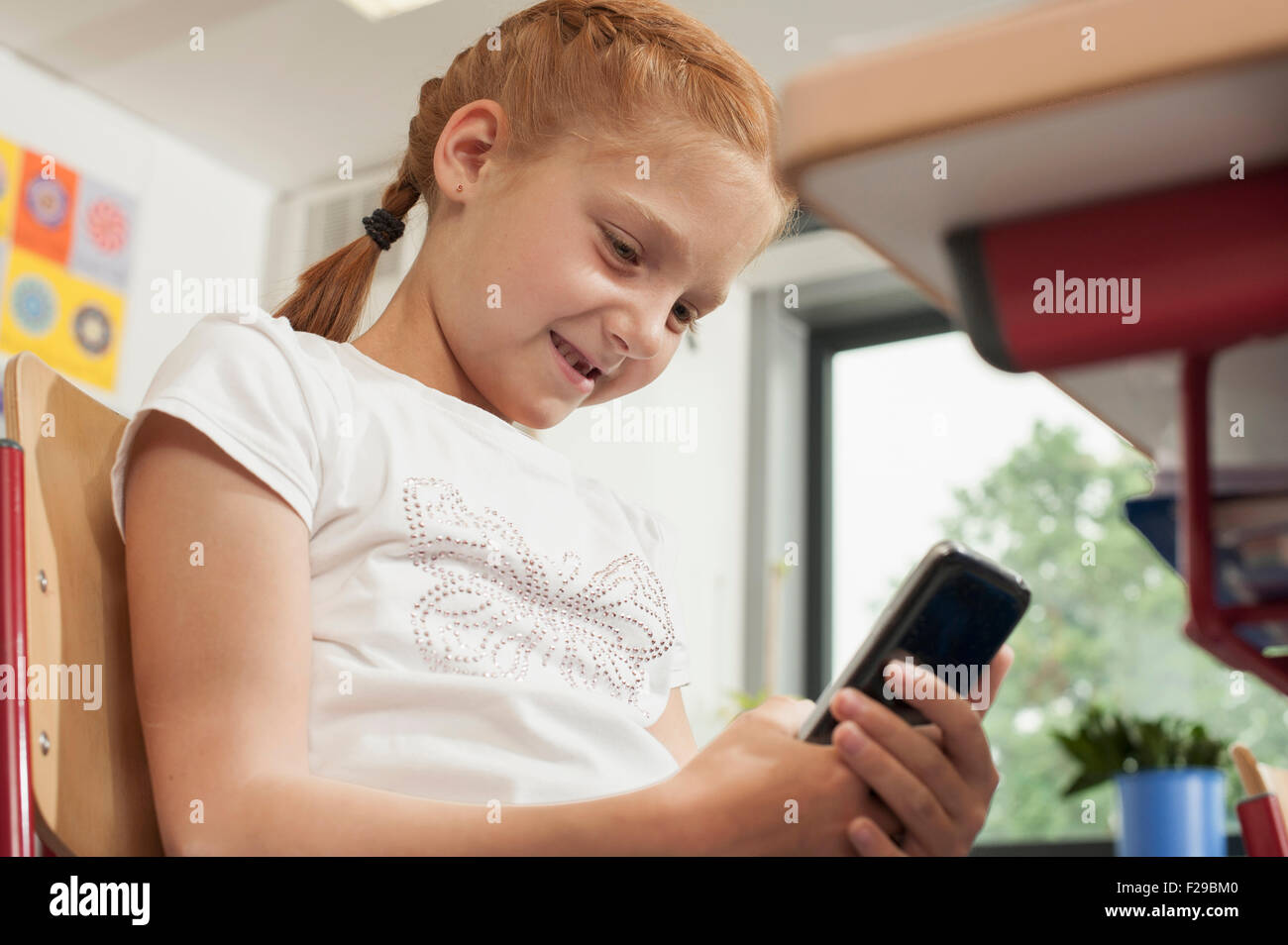 Low angle view of a schoolgirl using a smart phone in classroom, Munich, Bavaria, Germany Stock Photo
