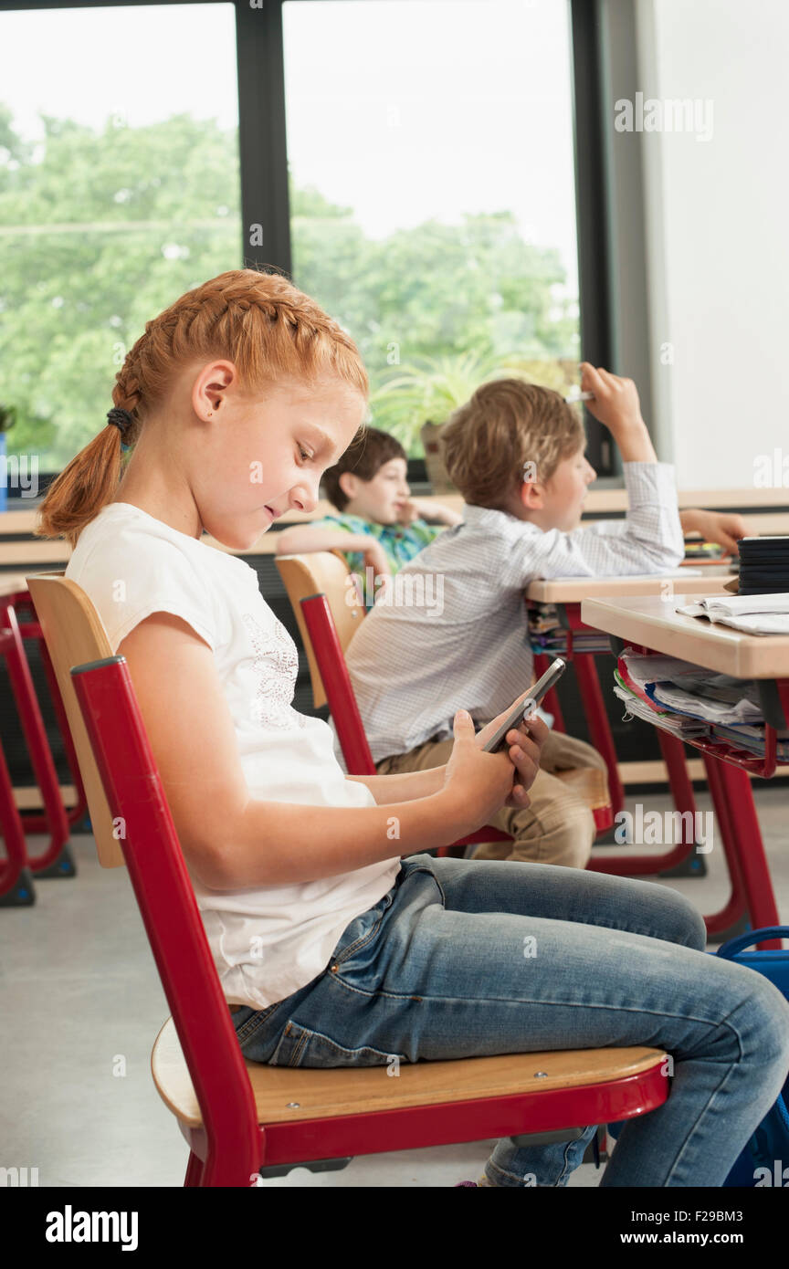 Side profile of a schoolgirl using a smart phone in classroom, Munich, Bavaria, Germany Stock Photo