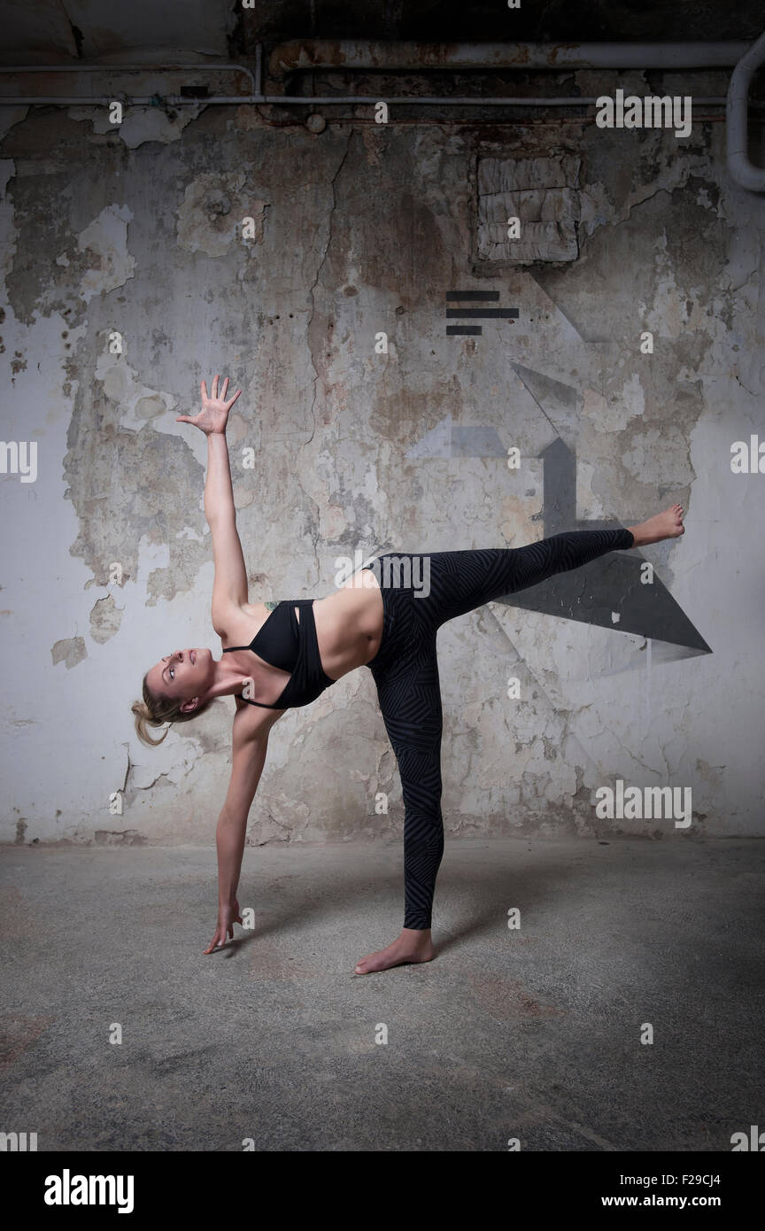 Mid adult woman practicing half moon pose in yoga studio, Munich, Bavaria, Germany Stock Photo