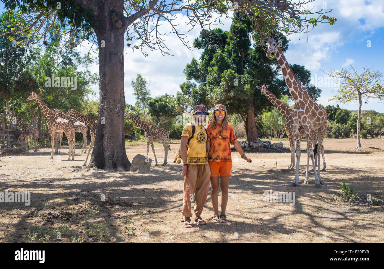 Happy family feeding giraffe during a trip to a city zoo on a hot summer day Stock Photo