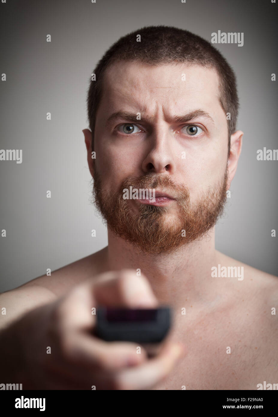 Zapping concept - annoyed man with tv remote control Stock Photo
