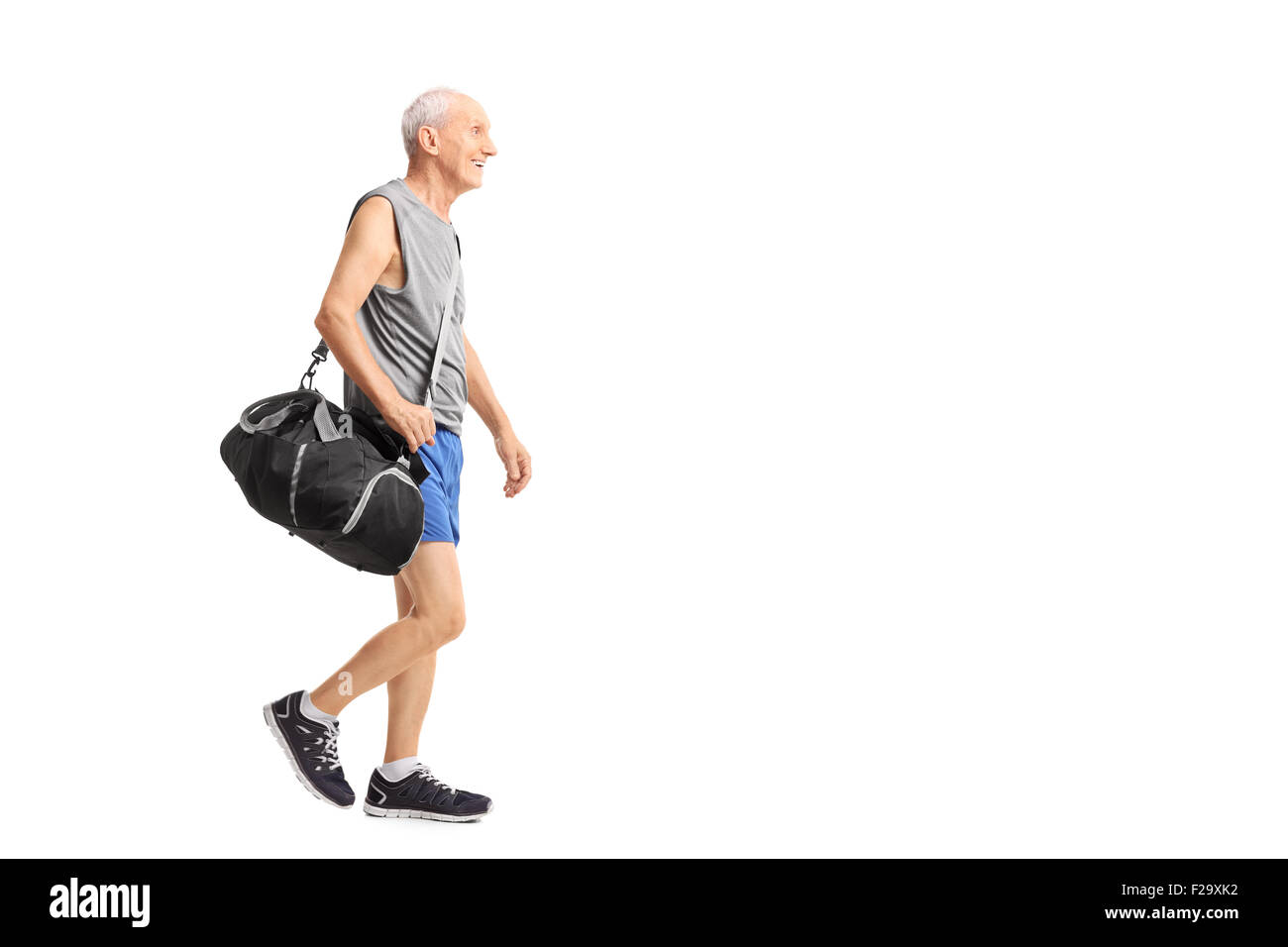 Full length profile shot of a senior man walking and carrying a sports bag isolated on white background Stock Photo