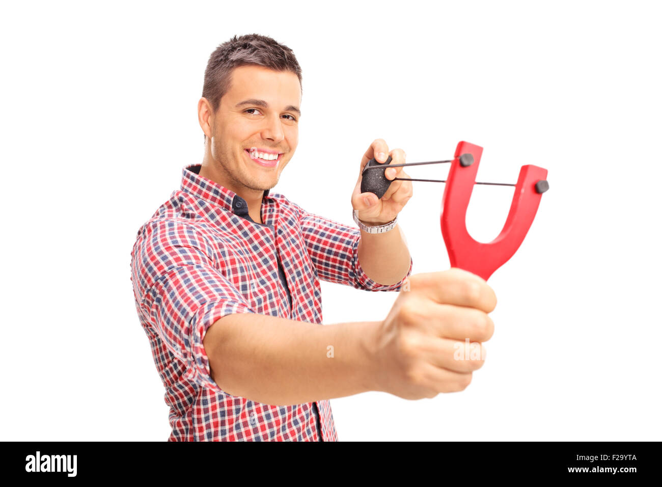 Young joyful guy shooting a rock from a slingshot and looking at the camera  isolated on white background Stock Photo - Alamy