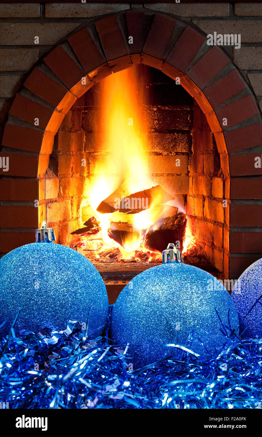 blue Christmas balls and tinsel with open fire in home fireplace Stock Photo