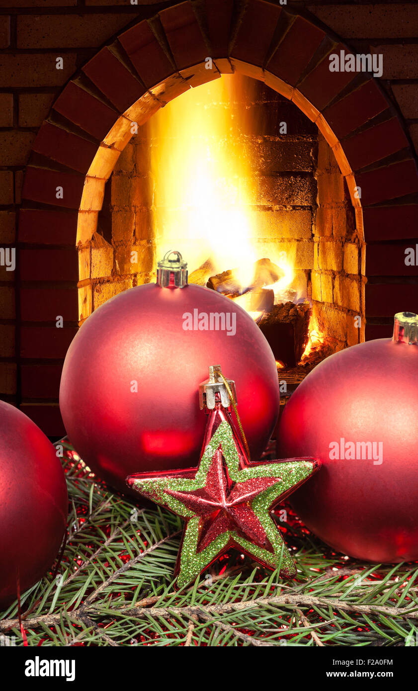 red star and Christmas balls on green spruce tree with open fire in home fireplace Stock Photo