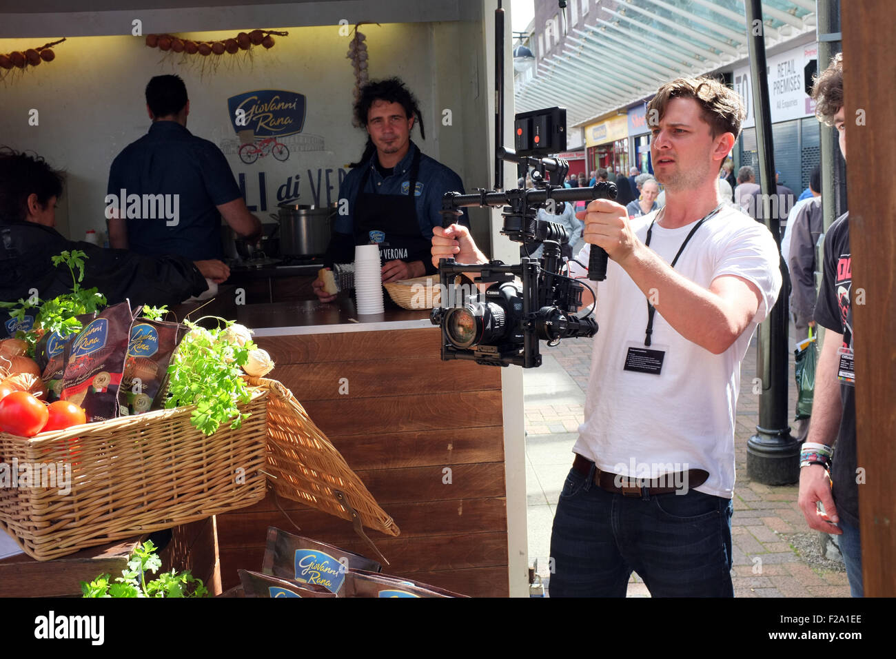 A videographer uses a Canon camera on a stability rig at a Food Festival event in Bolton Town Centre, England UK Stock Photo