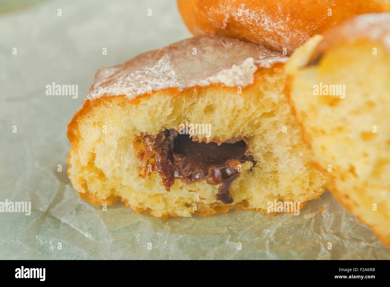 Sweet sugary donuts filled with chocolate cream on rustic wooden kitchen table, tasty bakery doughnuts, selective focus Stock Photo