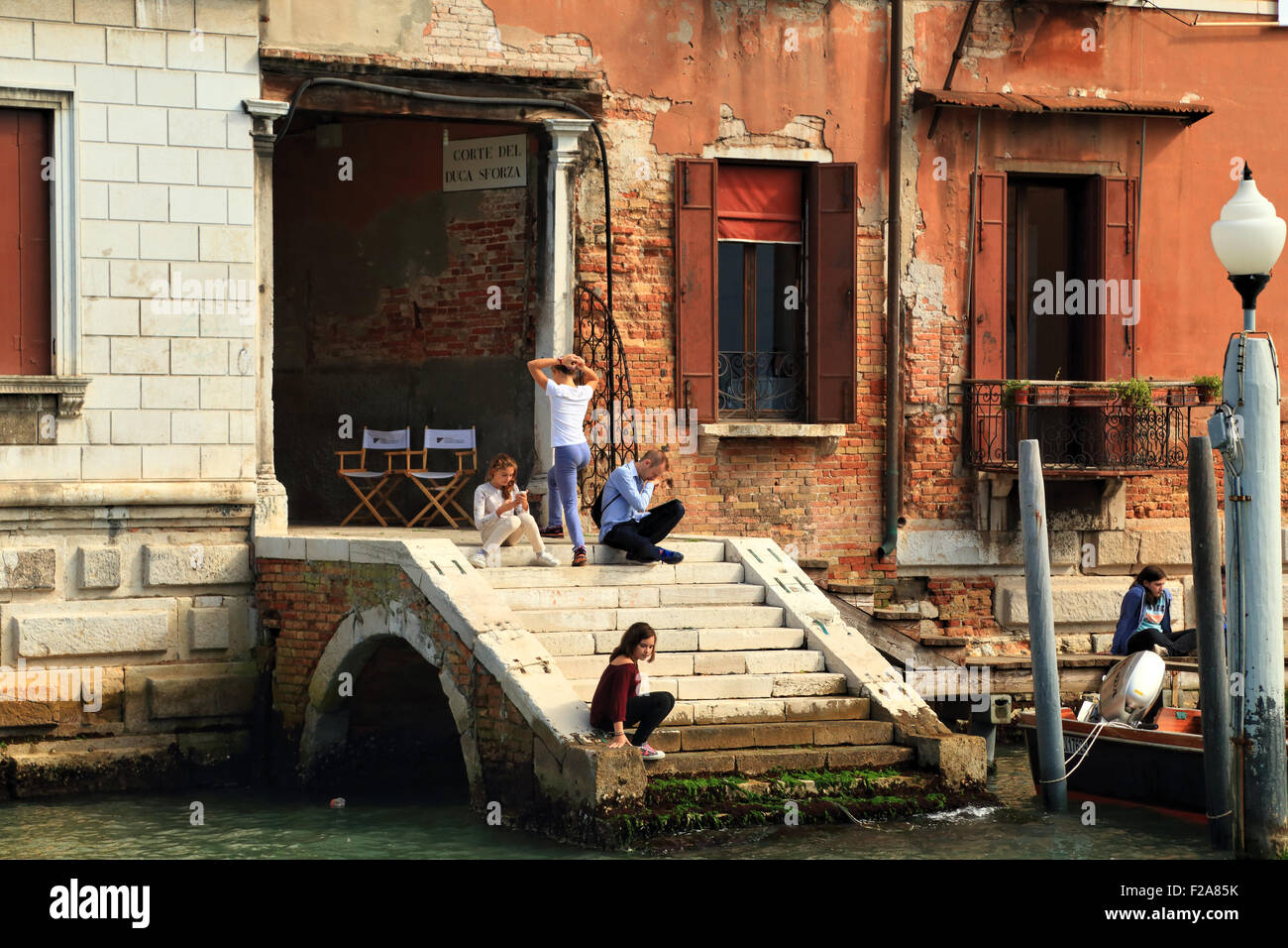 Teenager having a break at the Grand Canal stairs of Palazzo Ca' del Duca Stock Photo