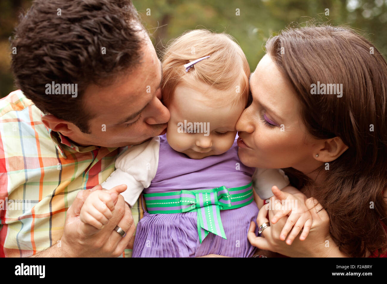 Kiss of love - happy parents with their cute baby girl Stock Photo ...