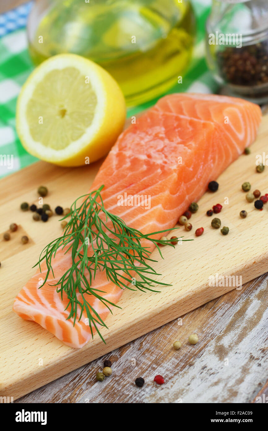 Raw salmon steak, pepper, dill and lemon on wooden board Stock Photo