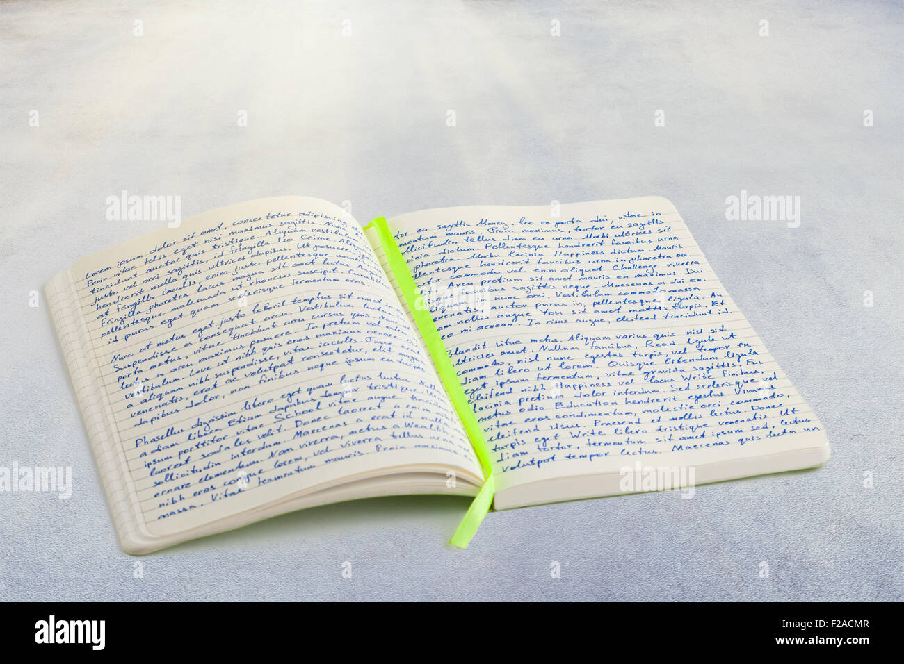 Open notebook with handwritten  lorem ipsum text and ribbon bookmark in the middle, laying on textured surface Stock Photo