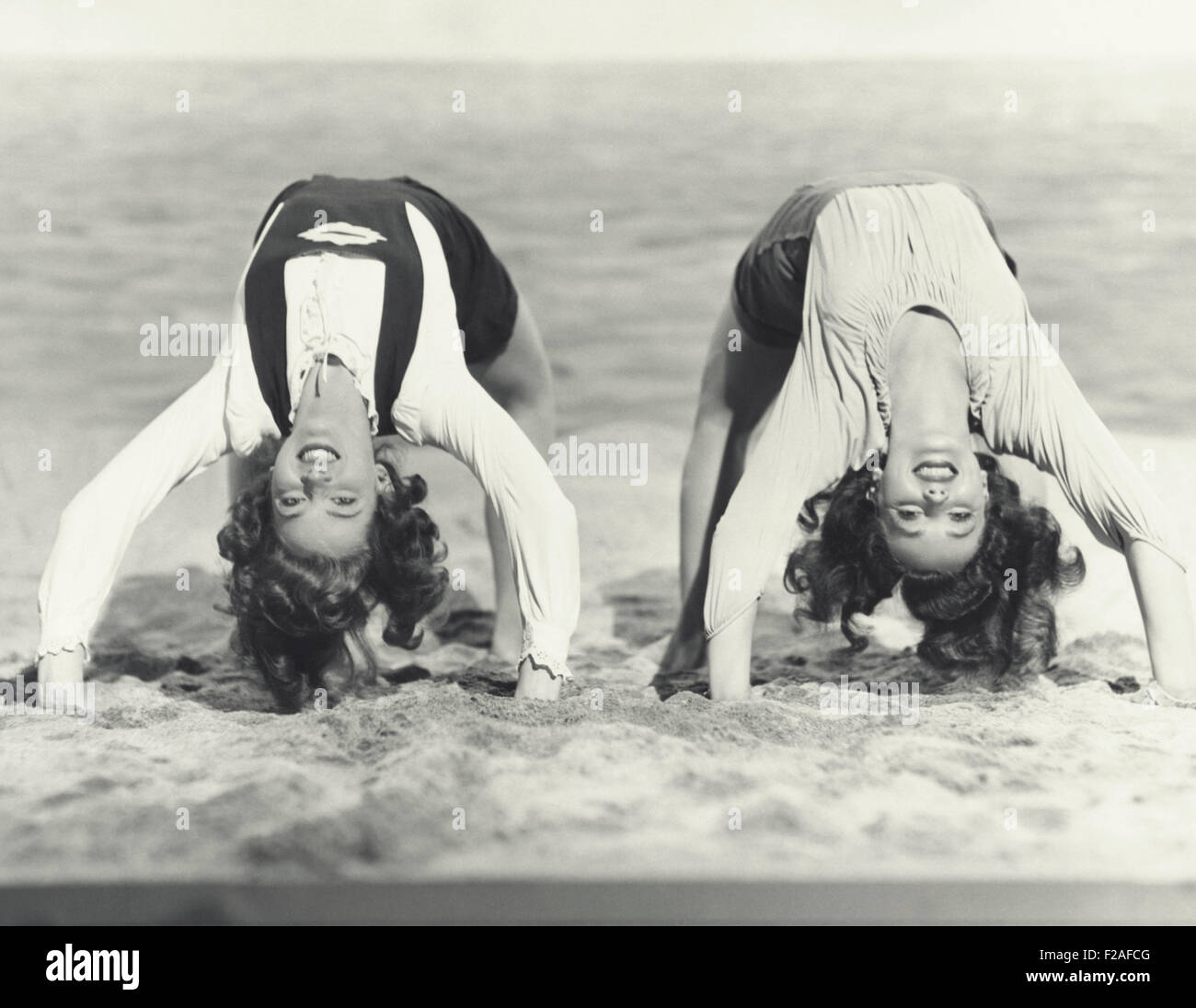 Two women doing backbends on the beach (OLVI008 OU479 F) Stock Photo
