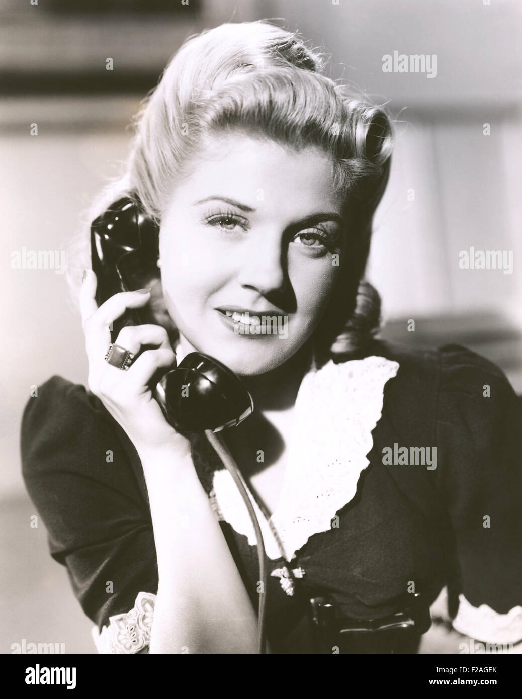 Blonde woman holding telephone receiver (OLVI008 OU144 F) Stock Photo