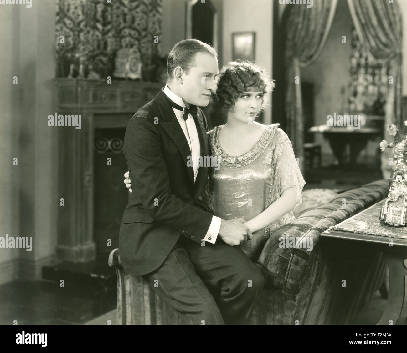 Couple sitting on edge of couch (OLVI007 OU857 F) Stock Photo