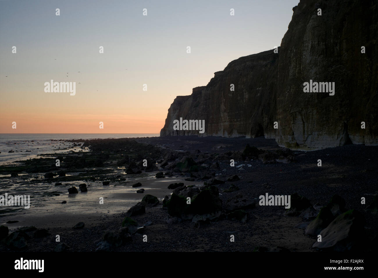 Sunrise behind cliffs, beach and sea, Normandy, France Stock Photo