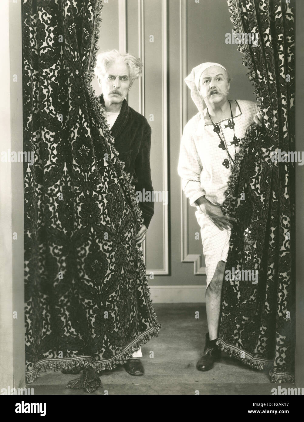 Two men spying from behind drapes (OLVI007 OU719 F) Stock Photo