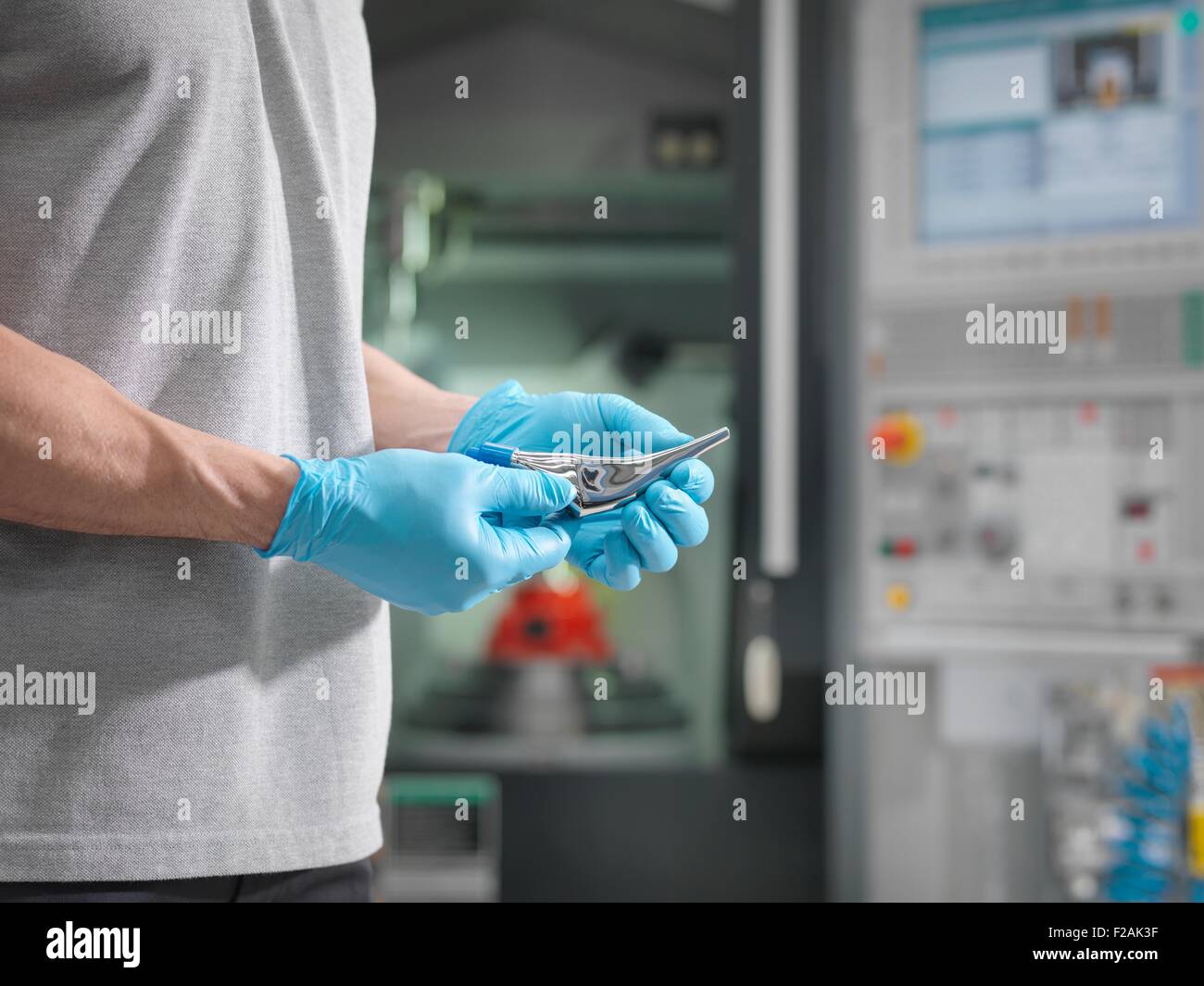 Engineer holding machined artificial hip joint in front of CNC lathe in orthopaedic factory Stock Photo