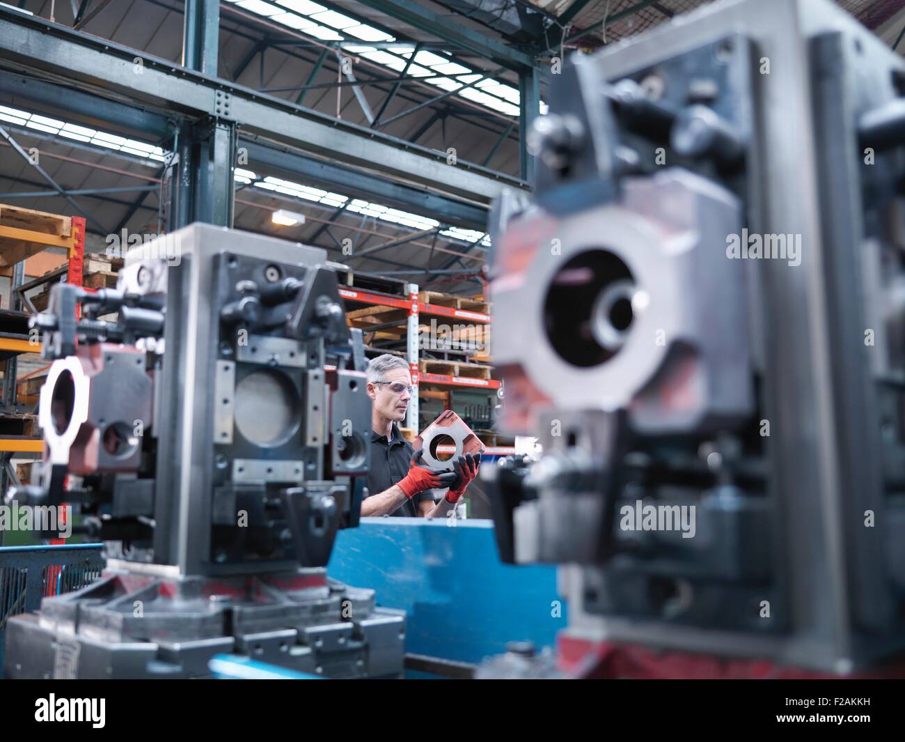 Engineer inspecting parts on automatic lathe in engineering factory Stock Photo