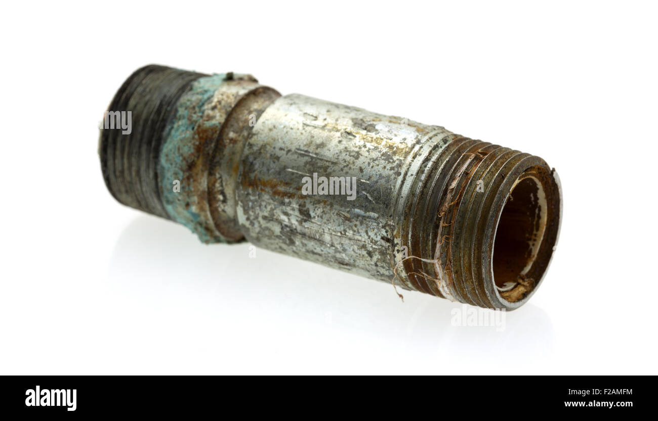 An old and leaking short pipe nipple with remains of pipe thread compound on a white background. Stock Photo