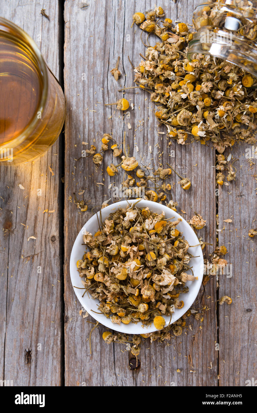Heap of dried Camomile (close-up shot) on wooden background Stock Photo