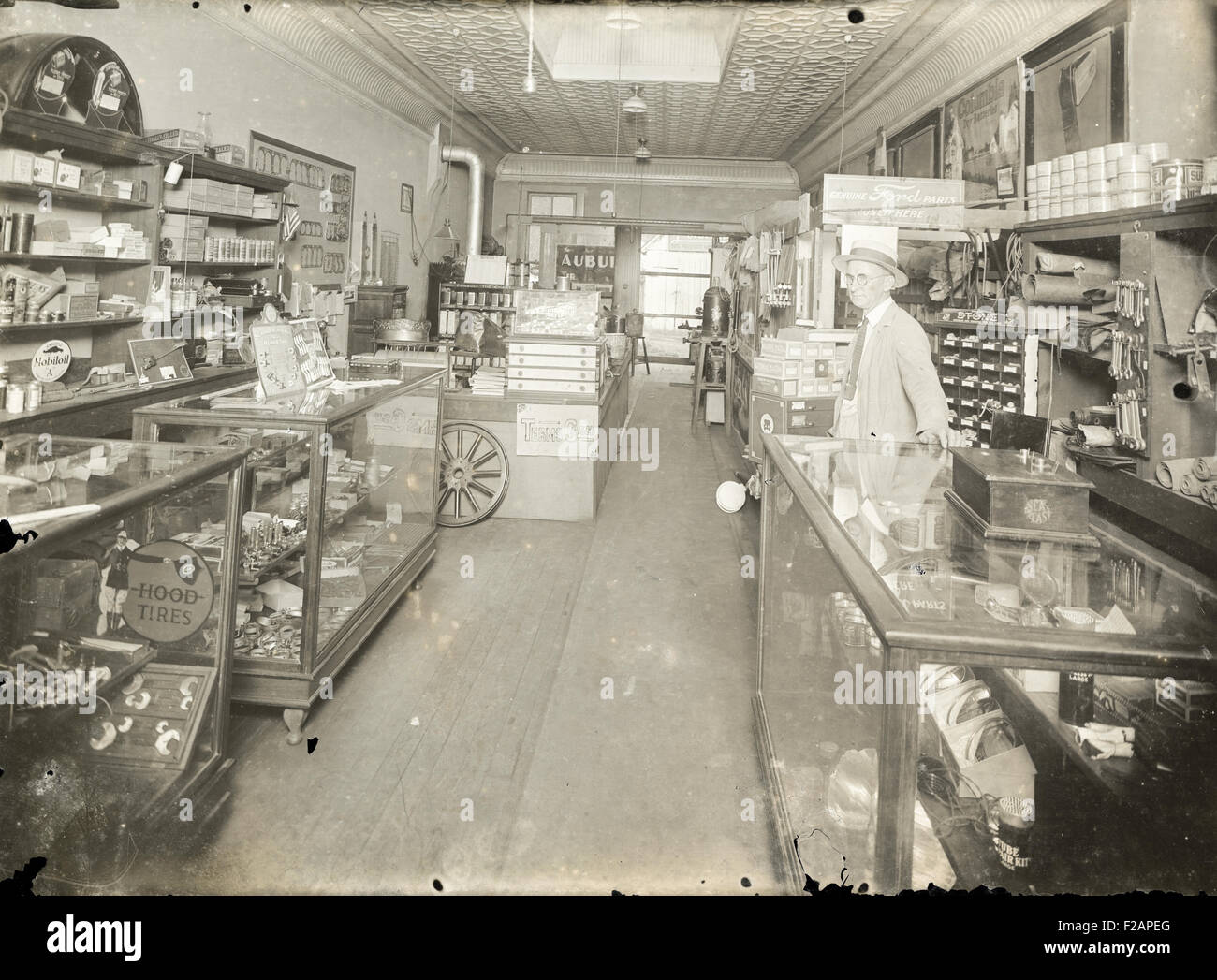 Antique circa 1910 photograph, interior of an auto parts store. Location, USA. Signage and advertising is visible for Genuine Ford Parts, Stone Rim Repair Parts, National Mazda, Columbia Dry Batteries, Hood Tires, Mobiloil A, Schrader Universal Valve Repair Tool, and Eveready Daylo. Stock Photo