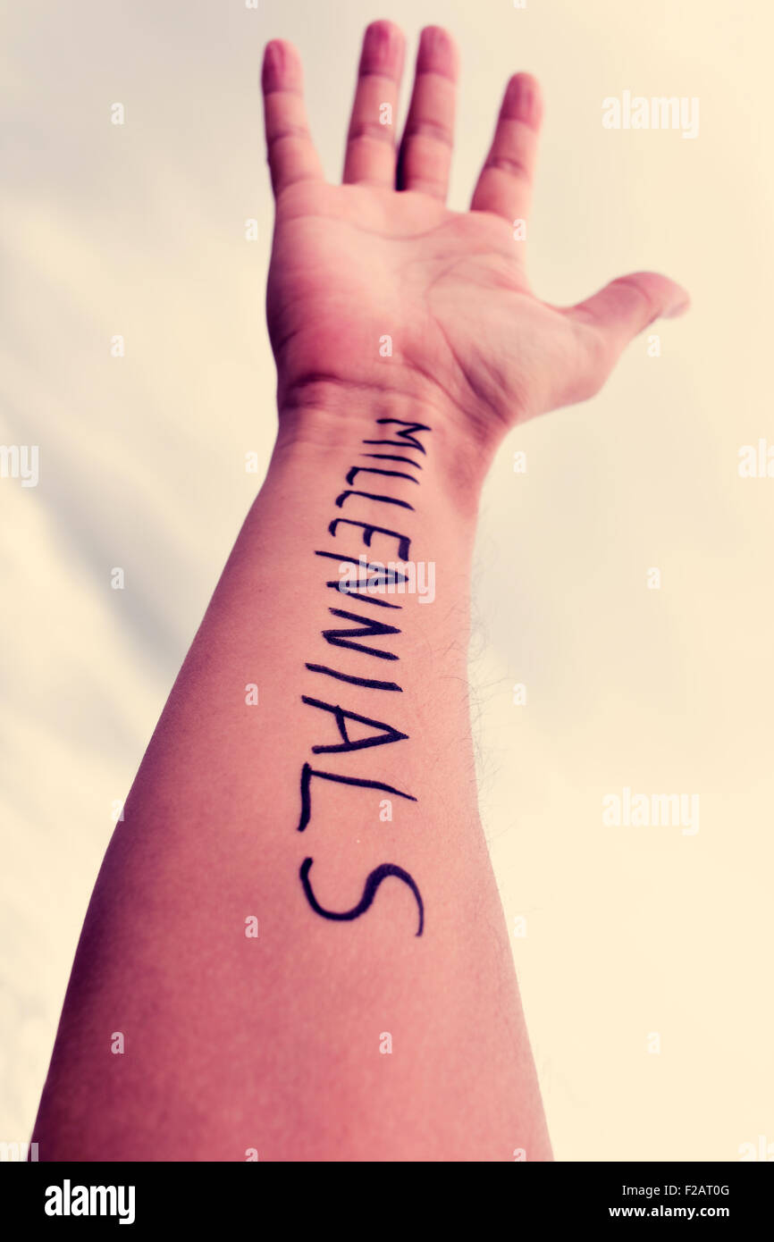 closeup of the arm of a young man with the word millennials written in it, against the sky, with a filter effect Stock Photo