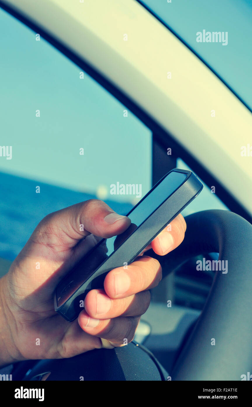 closeup of a man using a smartphone while driving a car Stock Photo