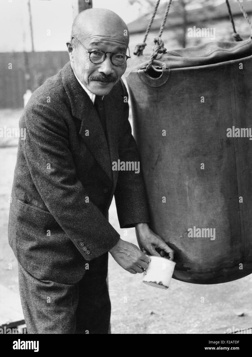 Japanese Ex-Premier Hideki Tojo, at Omori Prison Camp for suspected war criminals. Nov. 9, 1945. After Japan's defeat he shot himself, but received medical care and recovered. He is drawing water from a storage bag. (CSU 2015 11 1701) Stock Photo