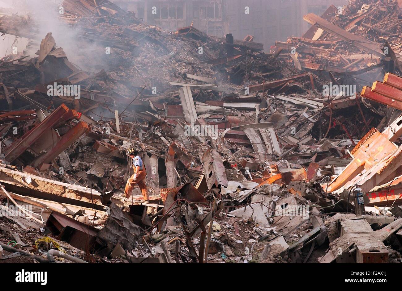 NYC Fire fighter walks over smouldering fires and wreckage at Ground Zero, Sept. 18, 2001. World Trade Center, New York City, after September 11, 2001 terrorist attacks. (BSLOC 2015 2 96) Stock Photo