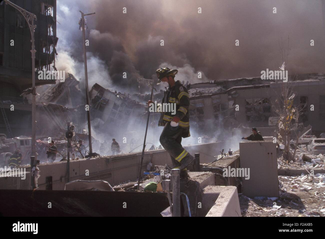 Fire fighters amid smoking rubble following September 11th terrorist attack on World Trade Center. At left is still standing WTC 6. At right is the destroyed North pedestrian bridge over West Side Highway (West St.). In the background is the burning pile of the collapsed WTC 1 (North Tower). New York City, Sept. 11, 2001. (BSLOC 2015 2 47) Stock Photo