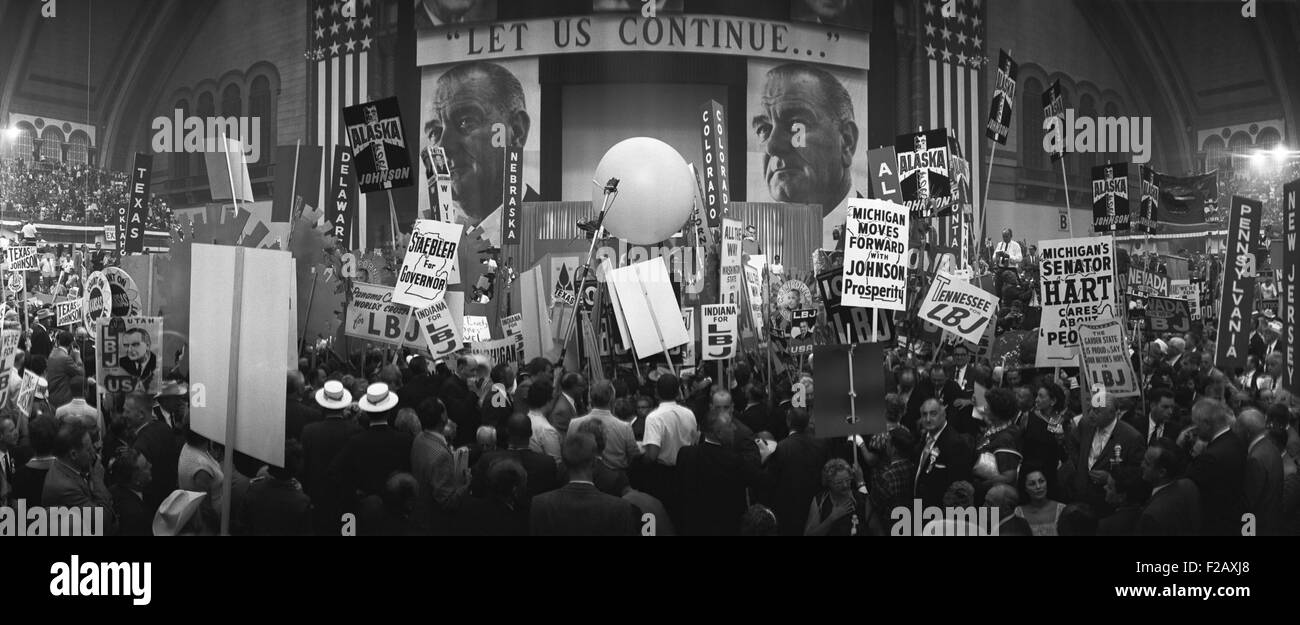 Delegates and stage at the 1964 Democratic National Convention, Atlantic City, New Jersey. Stage has two large photos of President Lyndon Johnson with an sign reading, 'Let us continue…', a reference to the legacy of assassinated president, John F. Kennedy. (BSLOC 2015 2 214) Stock Photo