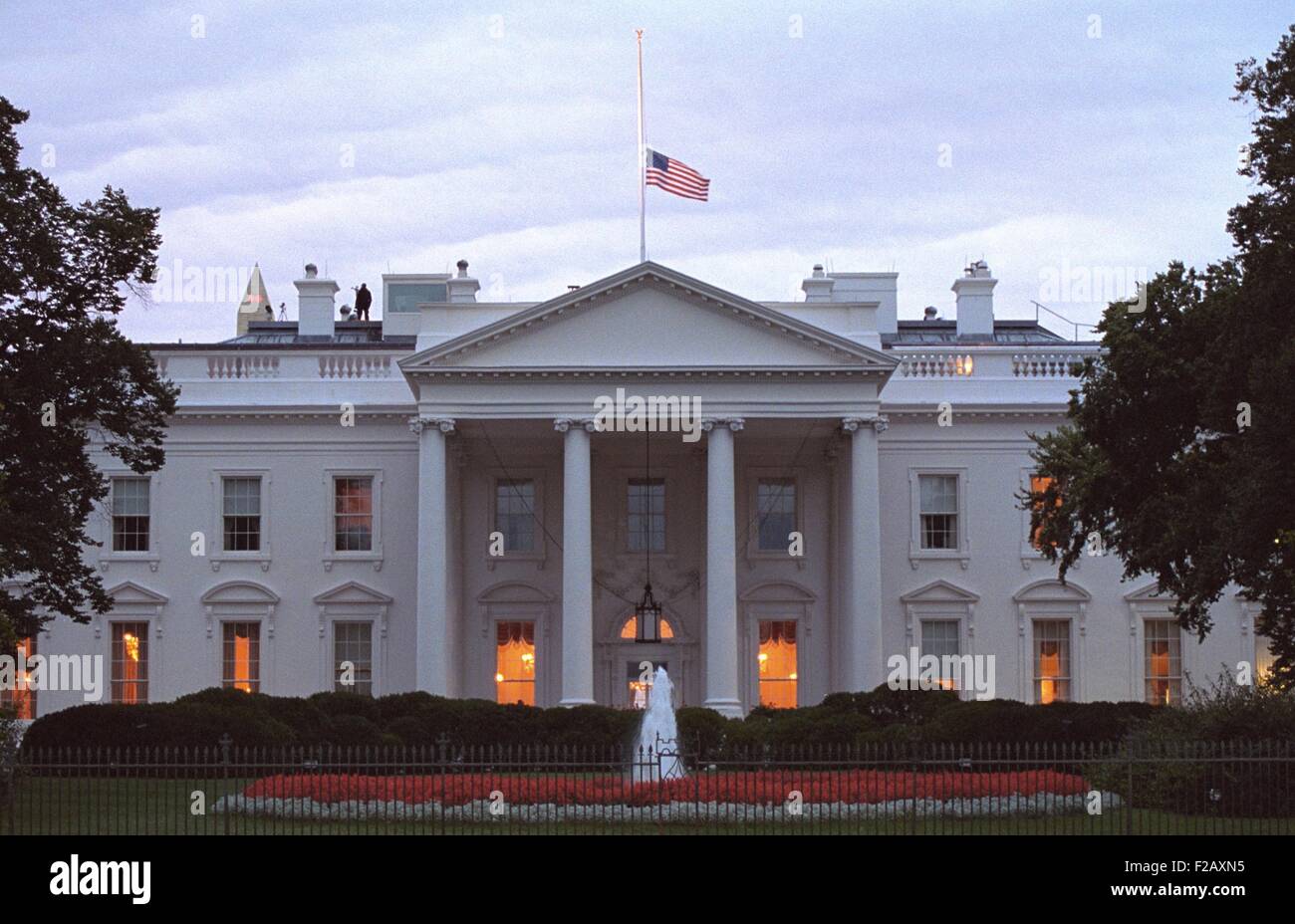 American flag flies at half-staff over the White House at sunrise Friday, Sept. 14, 2001. 3 days following the 9-11 Terrorist Attacks, counter assault team members are posted on the roof. (BSLOC 2015 2 148) Stock Photo