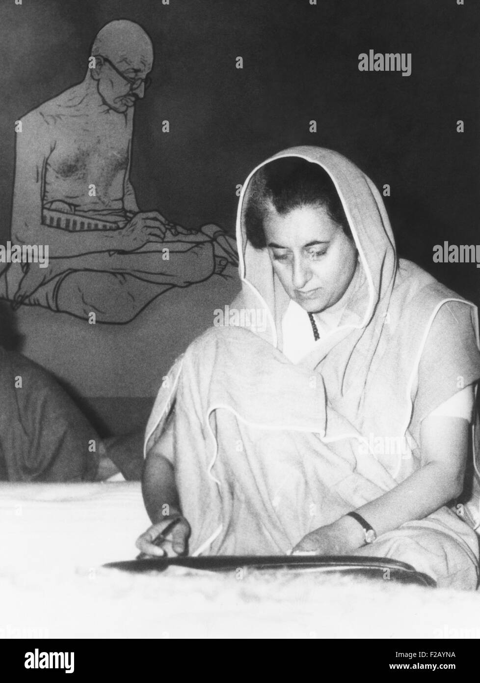 Indian Prime Minister Indira Gandhi during the annual session of the ruling Congress Party. Feb. 2, 1966. Seated on the floor, she meets her fellow countryman in the style of Mahatma Gandhi, pictured behind her. (CSU 2015 9 728) Stock Photo