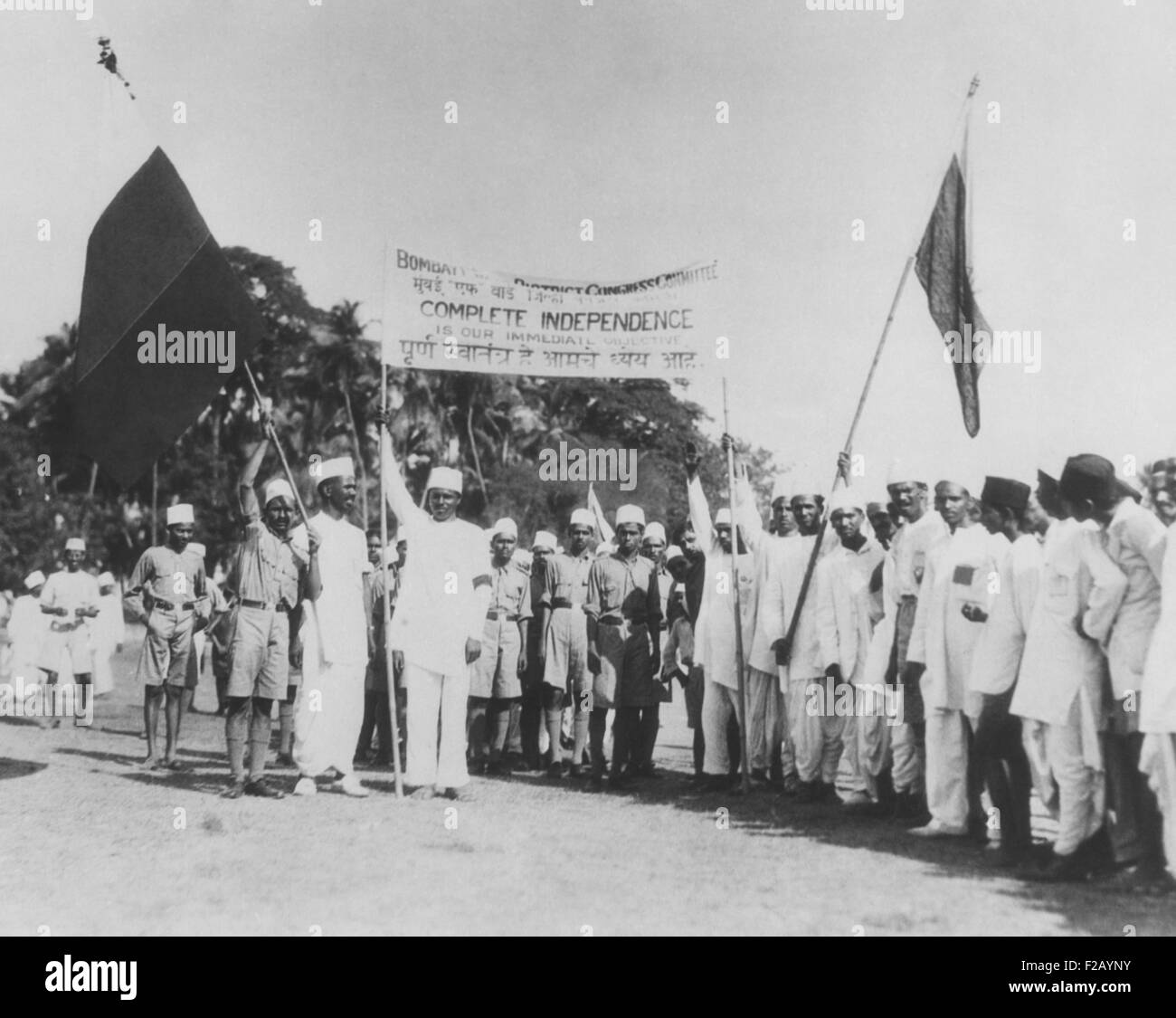'Satyagrahi' volunteers in Bombay (Mumbai) salute the National Congress flag. India, May 1930. The term 'satyagraha' was developed by Mahatma Gandhi, loosely translated as 'insistence on truth'. These protesters hold a sign, 'Complete Independence is Our Immediate Objective.' (CSU 2015 9 714) Stock Photo