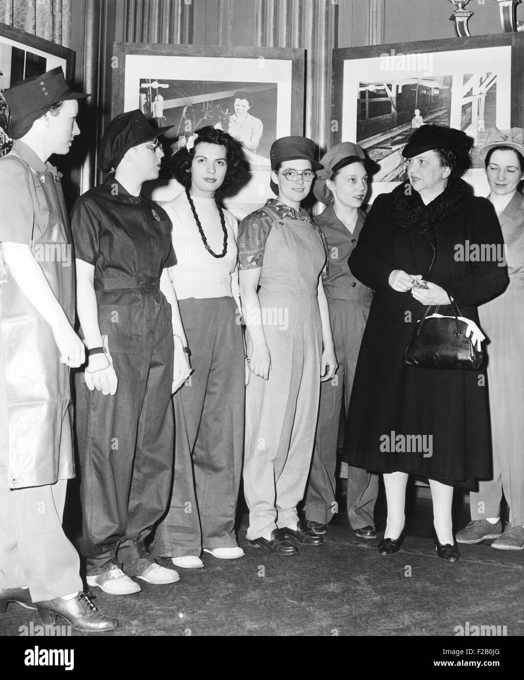 Secretary of Labor Frances Perkins examines work clothes for women. March 1, 1943. The work clothes for women were designed to promote safety and efficiency. The third model from left demonstrated how a female war worker SHOULD NOT be attired, in contrast to approved garb. (CSU 2015 9 1076) Stock Photo