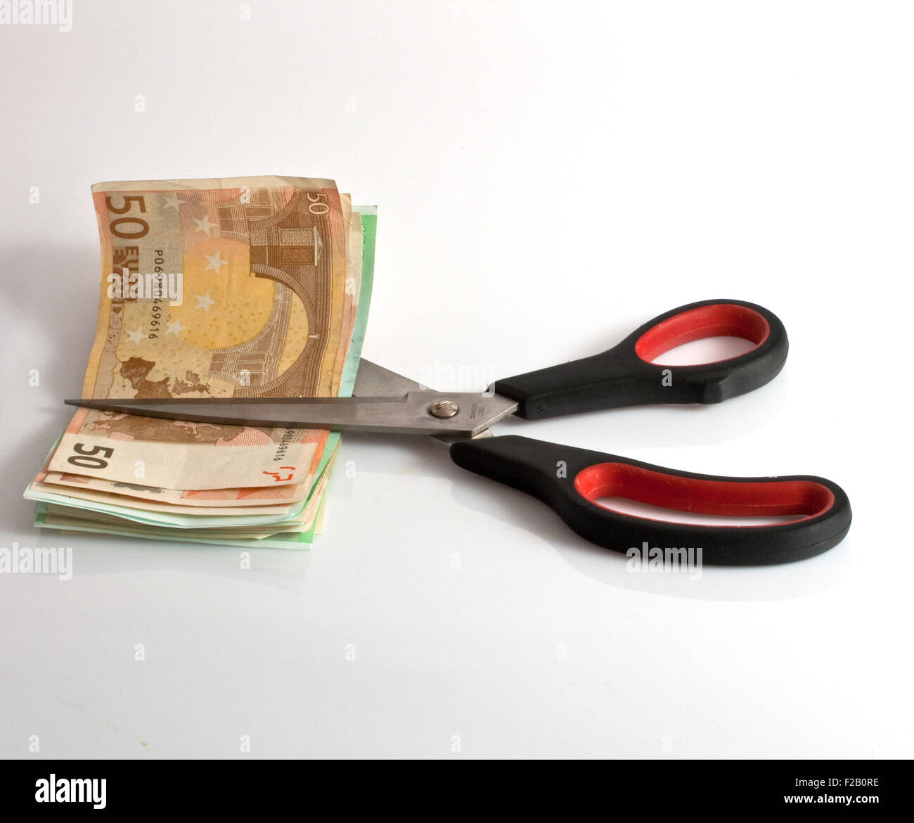 Scissors cutting the money, white background Stock Photo