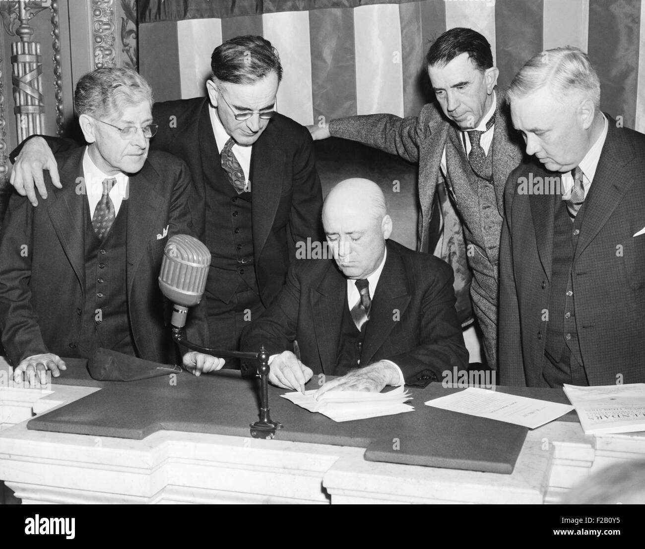 House Speaker, Sam Rayburn, seated on House rostrum, signing the Neutrality Revision Bill. Nov 13, 1941. L-R: Patrick Boland, Democratic whip; John McCormick, Majority Leader; Howard Smith, VA; and Lansdale Sasscer, MD. It allowed the American Merchant fleet to sail directly to Allied ports in the war zone under the protection of their warships. (CSU 2015 9 1033) Stock Photo