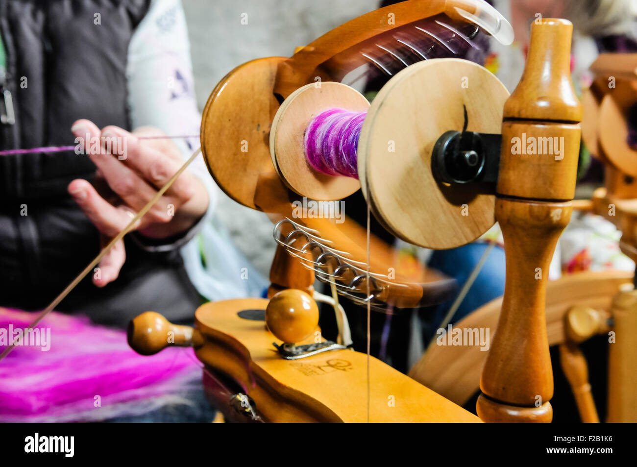 A woman spins wool using a traditional spinning wheel. Stock Photo