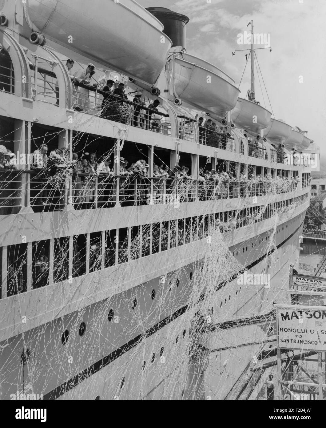 S.S. Lurline leaving Honolulu in the 1930s. Serpentine streams down her sides, and passengers wear fragrant flower leis as she pulls away from the pier. - (BSLOC 2015 1 234) Stock Photo