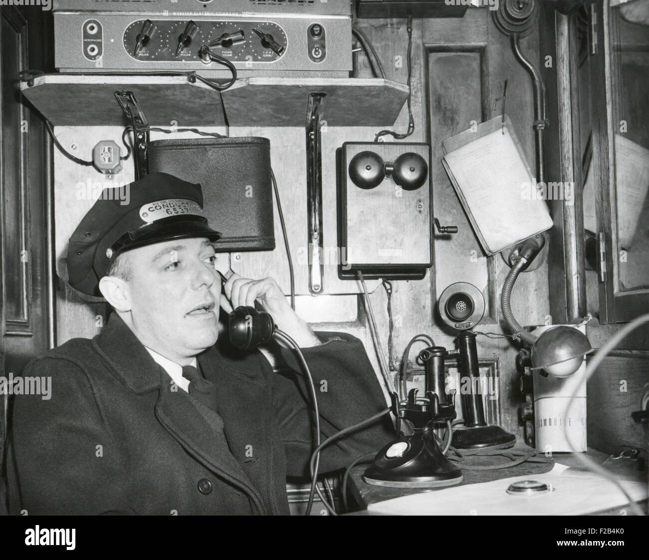 Railroad conductor uses an on board telephone to communicate with other parts of the train. Ca. 1930's - (BSLOC 2015 1 231) Stock Photo