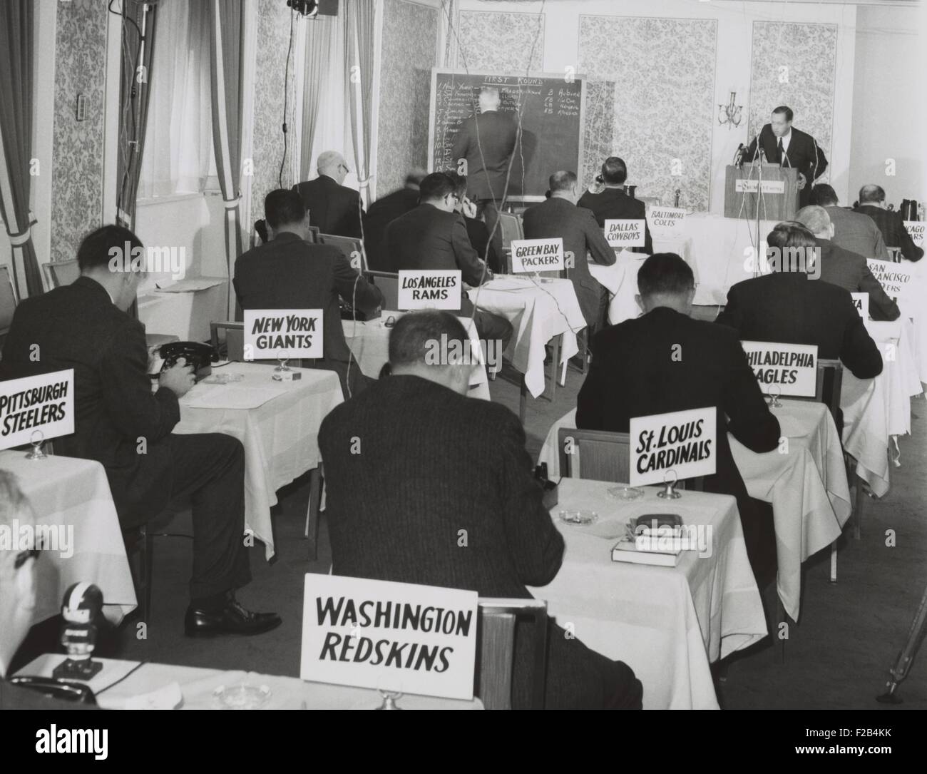 National Football League draft meeting in New York, Nov. 28, 1964. Commissioner Pete Rozelle reads the picks as representatives Stock Photo
