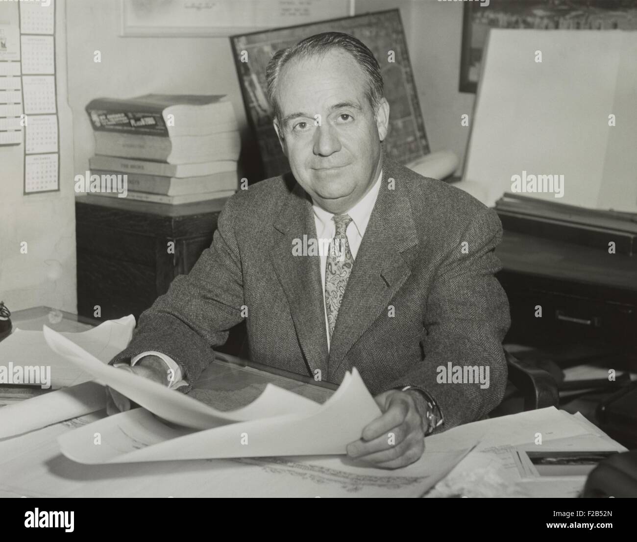 Robert Trent Jones, golf course architect, sitting at desk and holding drawings in 1953. - (BSLOC_2015_1_122) Stock Photo