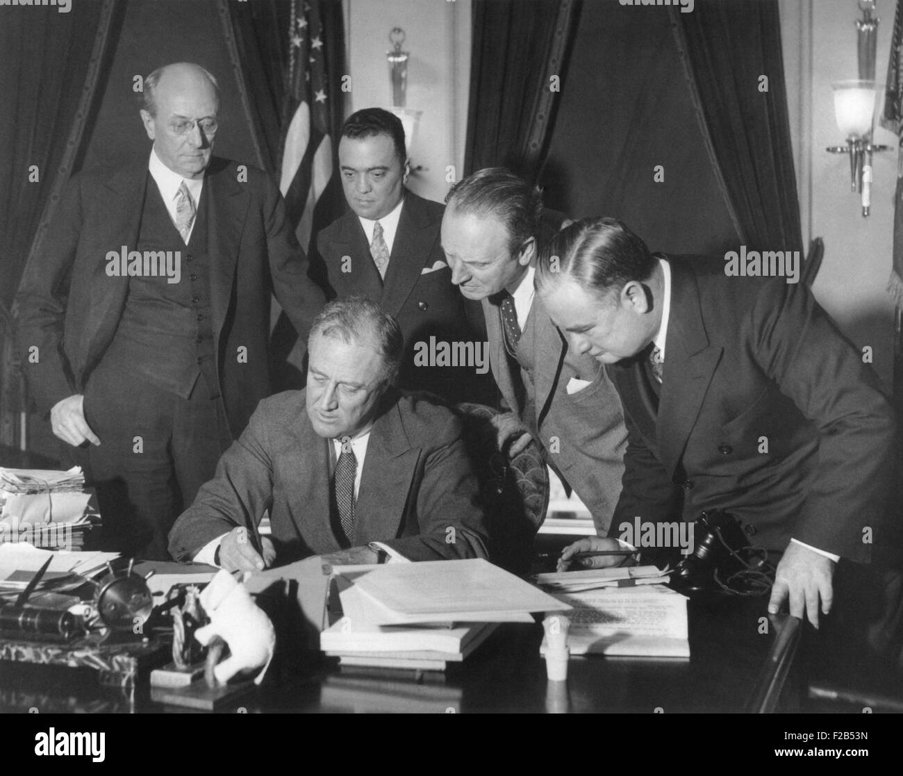 President Franklin Roosevelt signing the 1934 crime bill into law. Looking on from left: Attorney General Homer Cummings; J. Edgar Hoover, Director of the Bureau of Investigation; unidentified; Assistant Attorney General Joseph Keenan. May 18, 1934. - (BSLOC 2015 1 10) Stock Photo