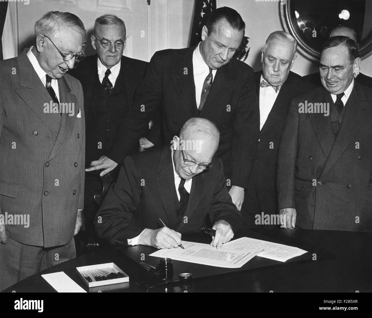 President Eisenhower signs House Joint Resolution 159. It authorized use of armed forces for protecting Formosa, and the Pescadores. Jan. 28, 1955. Standing, L-R: Walter George; John Foster Dulles; Sen. William Knowland; Sen. Alexander Wiley; Carl Albert. - (BSLOC 2014 16 233) Stock Photo