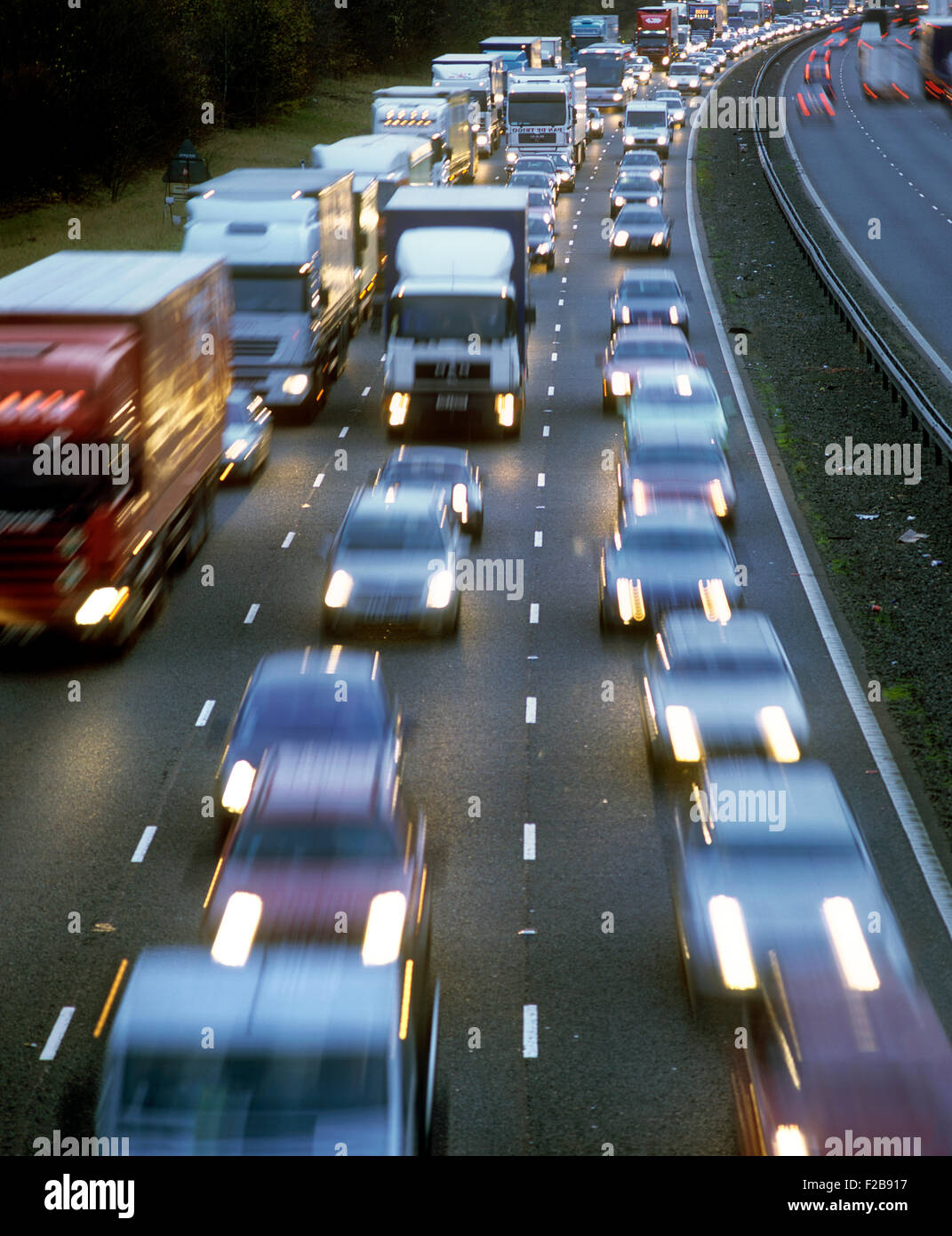 Bumper-to-bumper, nose-to-tail heavy traffic on a motorway in poor light.. Stock Photo