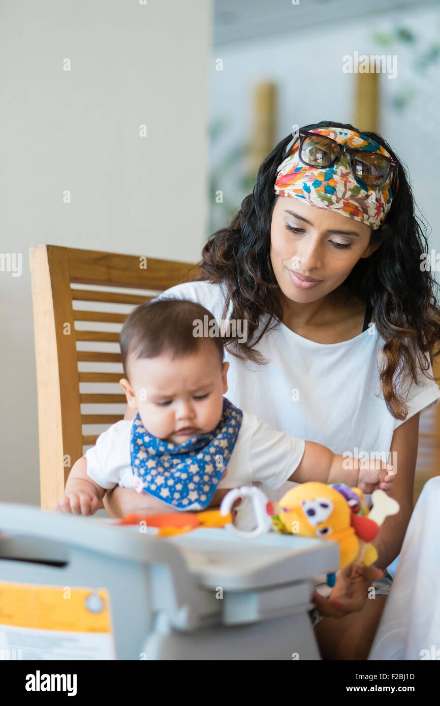 Beautiful hispanic woman with baby boy on her lap playing with toys Stock Photo